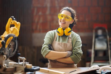 A young woman in safety glasses and hearing protection in a woodworking shop