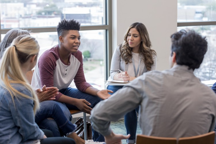 A mentor and a group of young people talking together in a circle